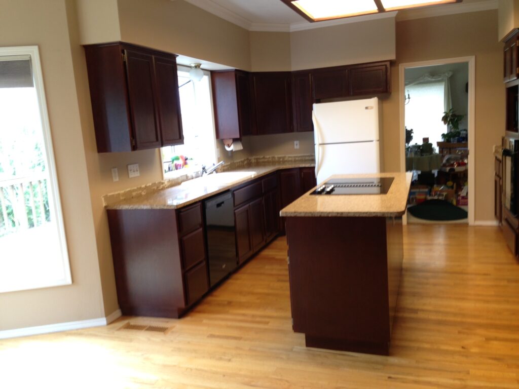 A kitchen with dark wood cabinets, a central island, a white refrigerator, and a light wood floor.