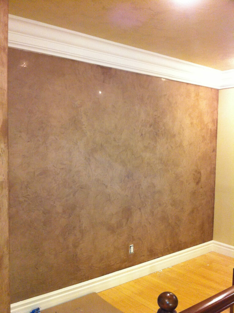 A plain brown wall with a white crown molding at the top and no decorations, in a room with light wood flooring.